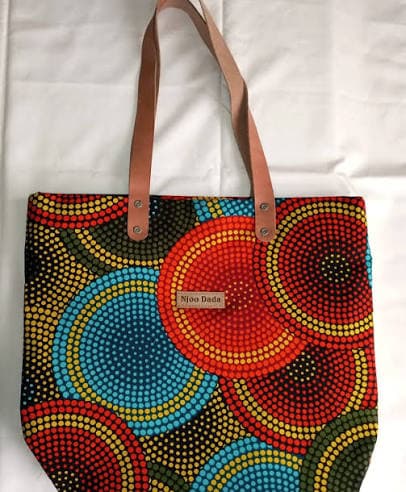 A Njoo Dada tote bag in a dotted circular African print pattern with leather handles.