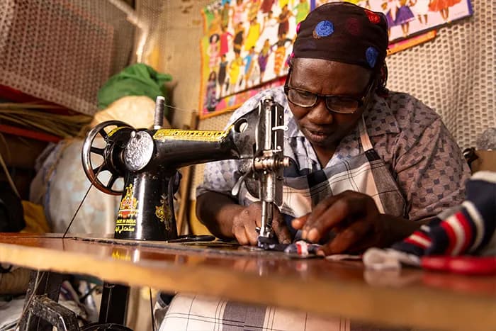 Serah working as a tailor, the skill that now supports her and her family.